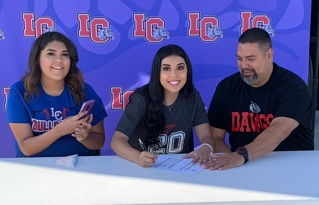 Las Cruces (NM) High School pitcher Destiny Flores signs her NJCAA Letter of Intent flanked by her sister Savannah and father Estevan.
